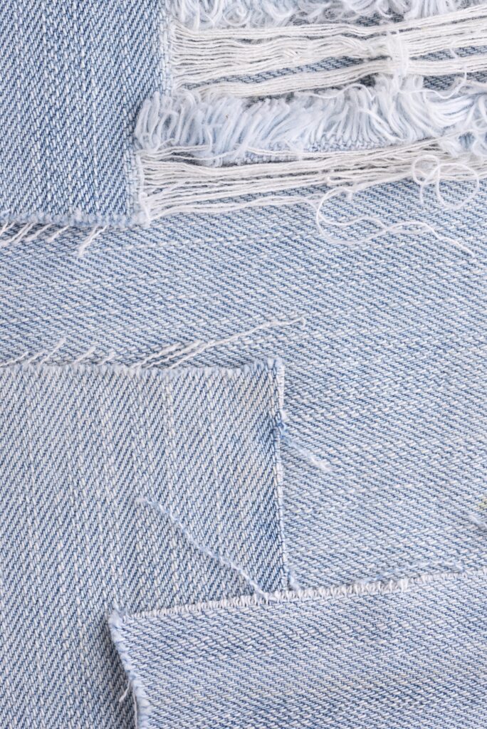 Tecido jeans sendo recortado para customização.