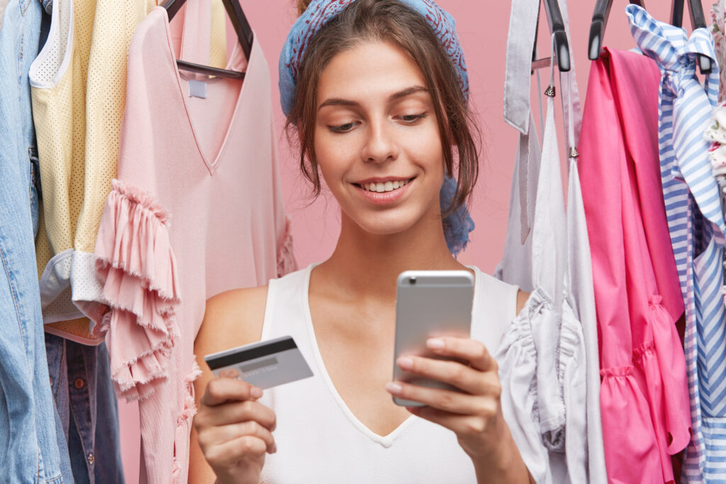 Mulher fazendo compras online com celular e cartão de crédito.