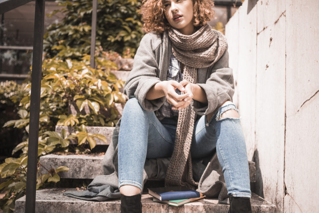 Pessoa na rua com look invernal sustentável: blazer, cachecol e calça reta.