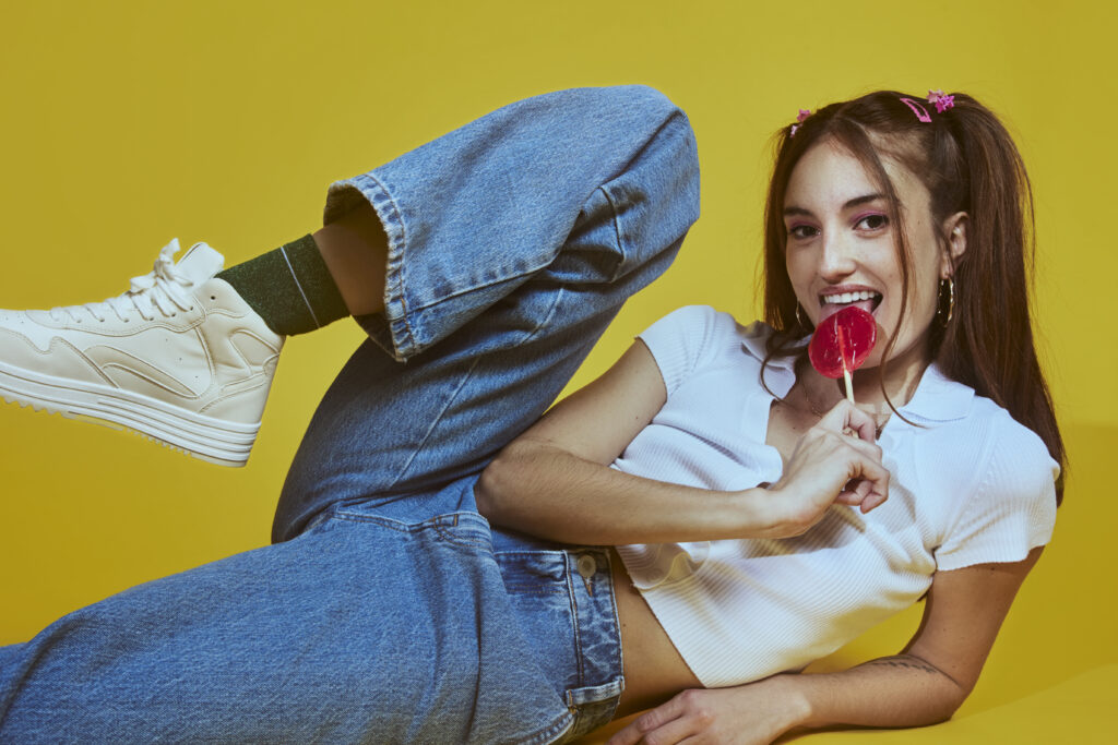 Mulher com look casual usando mom jeans, top e tênis.