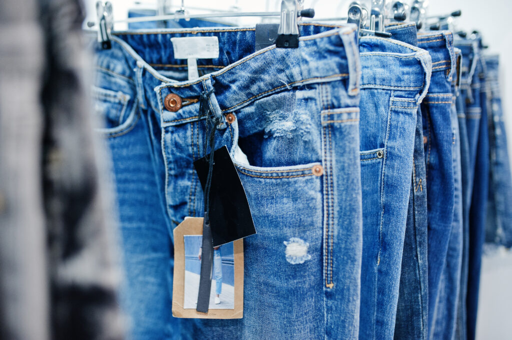 Cabides com calças jeans variadas em loja de segunda mão.