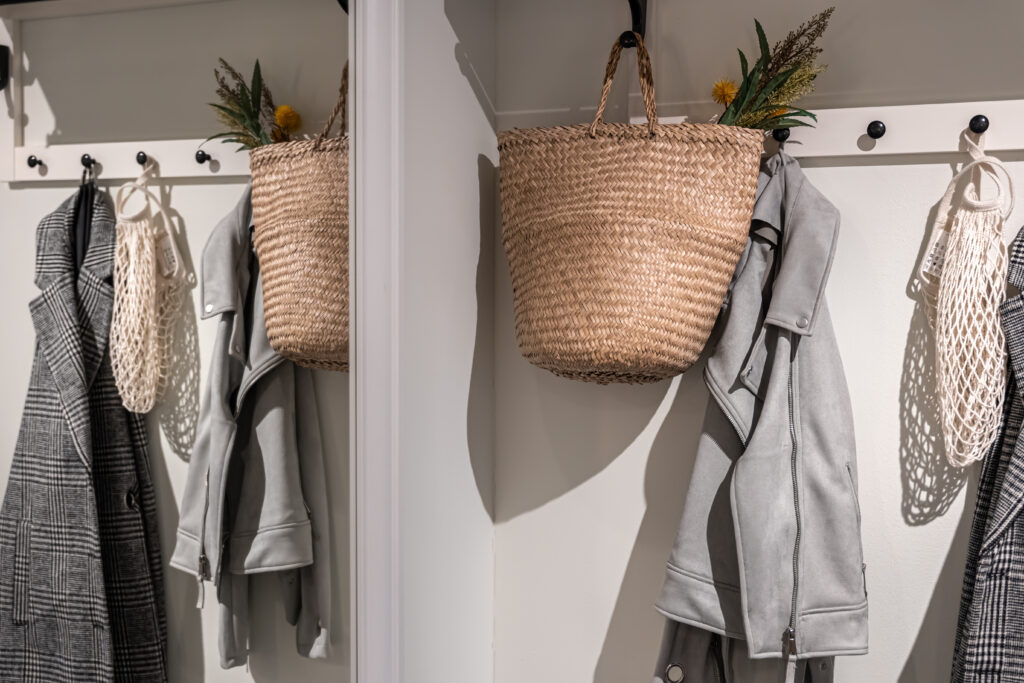 Armário com cabides de madeira, com roupas em tons neutros.