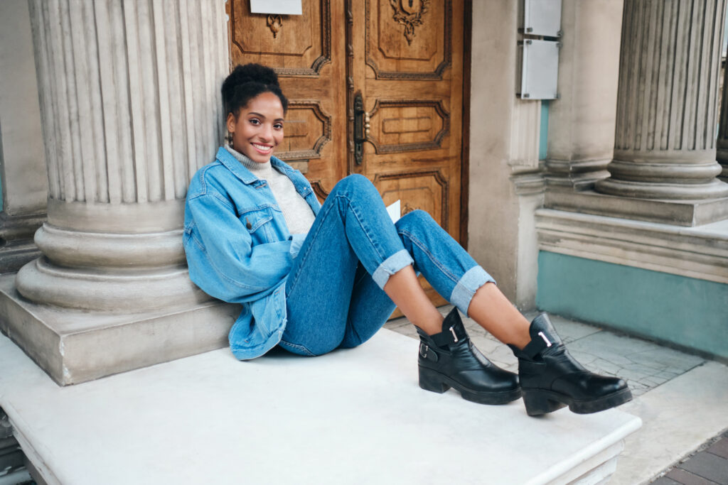 Mulher usando jaqueta retrô, jeans moderno e coturno em look urbano.