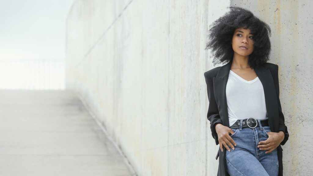 Mulher usando blazer preto com jeans e camiseta branca.