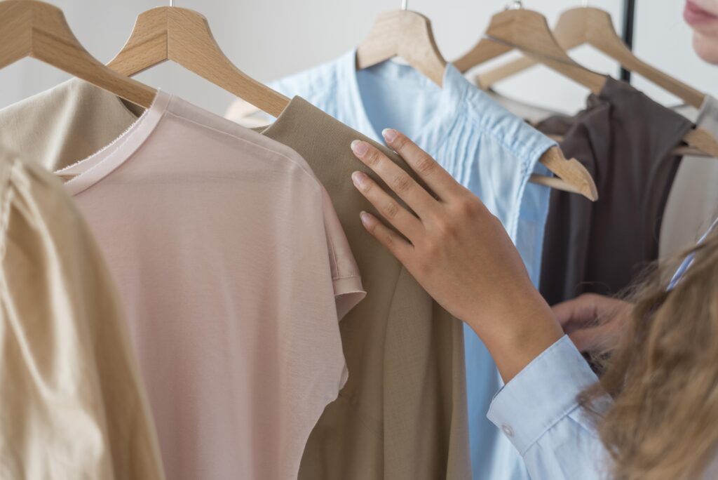 Imagem de mão feminina procurando roupas em um brechó