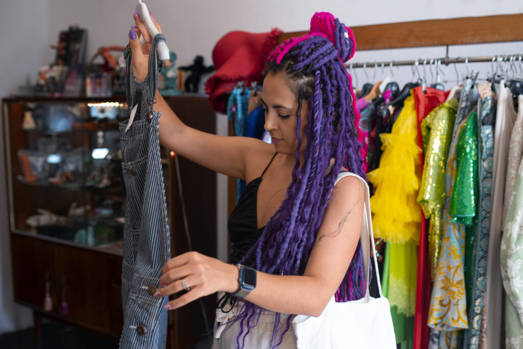 Roupas coloridas em arara de brechó com ambiente aconchegante e decoração retrô.