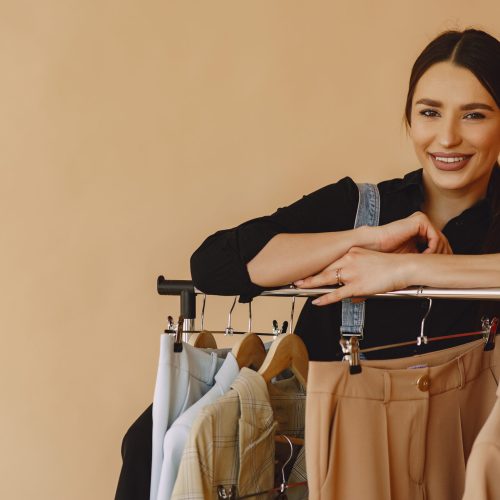 Woman on a brown background. Lady with clothes on a hanger.